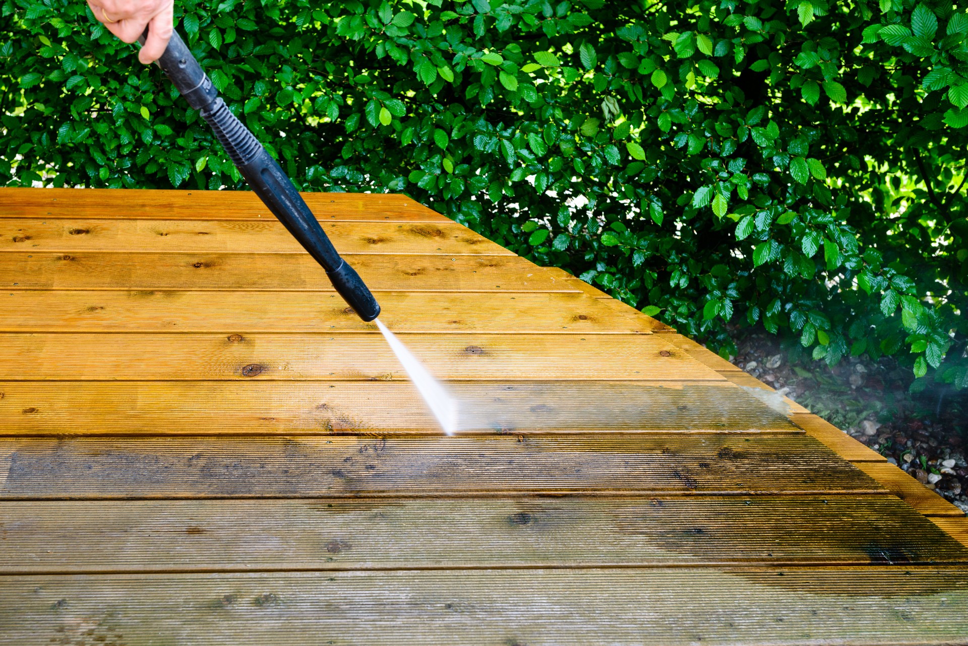 cleaning terrace with a power washer - high water pressure cleaner on wooden terrace surface